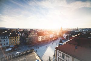 Marktplatz einer deutschen Kleinstadt. Hinter dem Kirchturm ist die Silhouette der Sonne.
