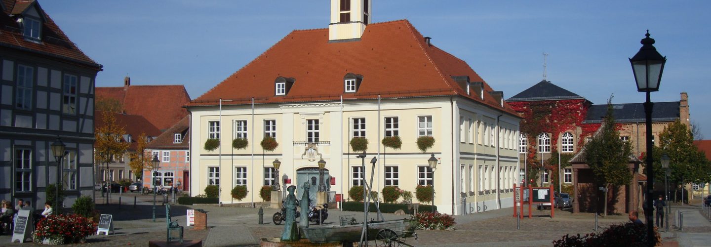 Der Markplatz in Angermünde. Im Zentrum des Fotos steht ein altes, weißes Gebäude, das aber hübsch renoviert wurde.