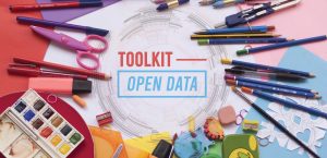 Ein Schreibtisch mit vielen Schreibutensilien wie etwas bunte Stifte. In der Mitte ist eine Grafik mit dem Schriftzug "Toolkit - Open Data"