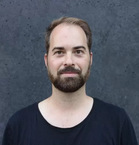 Portraitfoto von Philipp Hentschel vor einem grauen Hintergrund.