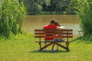 Ein Paar sitzt auf einer Bank und schaut auf einen See.